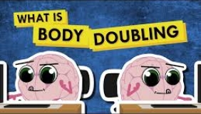 Two cartoon brains with big eyes sit at desks next to each other, representing body doubling. Above them, bold yellow and black text reads "What is Body Doubling" on a blue background.