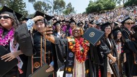 Proud graduates holding up their degrees on Commencement Day