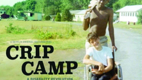  Poster for the Netflix documentary Crip Camp: A Disability Revolution. The image shows a young man in a wheelchair smiling, being pushed by another young man along a sunny road at a camp with cabins and trees in the background. Text on the image reads: “From Executive Producers President Barack Obama and Michelle Obama,” “A Netflix Original Documentary,” and “Winner Audience Award: U.S. Documentary, Sundance Film Festival 2020.”