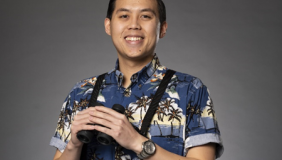 Man with binoculars in front of gray background