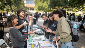 oxy students at a table at the involvement fair on the quad smiling and laughing