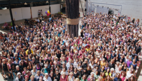 A large crowd of people standing together around an art sculpture