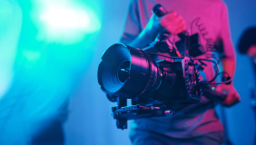 a cameraman holding a film camera with a colored background