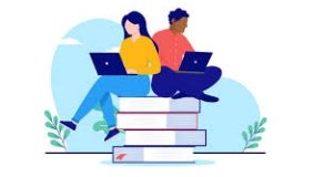 A female and a male sitting on a stack of books looking at their laptops