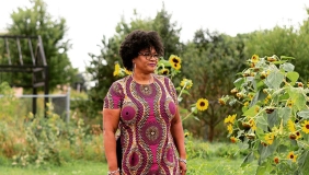 monica white in a green farm with sunflowers