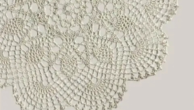 Close up of white lace doily on beige background 