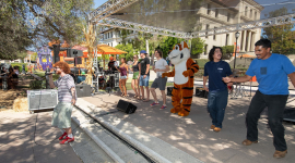 Occidental College students dancing in a group on campus with Oswald the Tiger