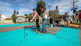 Two students painting the asphalt on Yosemite Way a bright teal color