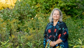 Robin Wall Kimmerer photographed outdoors in front of a green setting with wildflowers
