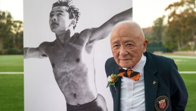 Sammy Lee Occidental College Olympian standing in front of a photo of him as a young man diving