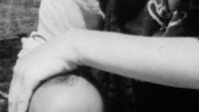 Still from the film Via Dolorosa by Oraib Toukan, abstract archival shot of a person&#039;s head and another person&#039;s arm