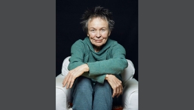 Portrait of Laurie Anderson with a teal sweater and a smile