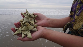 Photo of two hands holding star shaped sculptures made of natural fibers. 