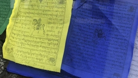 Close up photo of prayer flags, one yellow one blue. 