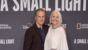 Two writers stand/pose next to each other at an industry event
