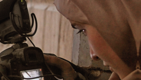 The cover of Refugee Cinema by Bruce Bennett and Katarzyna Marciniak shows a close-up of a woman in a headscarf looking down at a Canon camera's flip screen while filming, set against a weathered plaster wall.