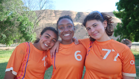 Three female Occidental students with ultimate frisbee jerseys, standing together