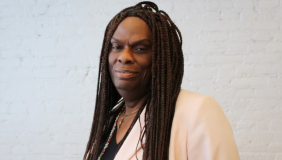 Portrait of Dee Farmer. She is wearing a cream colored shirt and looking into the camera smiling. 