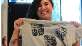 Photo of a person holding up a shirt and smiling. 