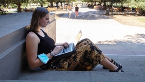 A student studying with her laptop by the library