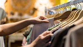 am image of two hands looking at clothing hung on racks