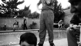 black &amp; white photo of people standing around a pool, foreground &amp; background