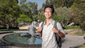 an occidental student poses for a picture in the Academic Quad with Gilman Fountain in the background.