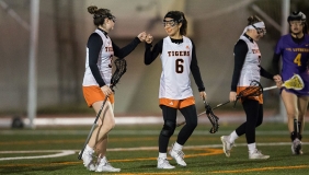 Two Oxy students playing women's lacrosse fist-bump each other
