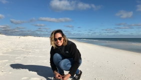 Dr. Caitlin Fong crouching on a beach