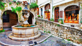 a picturesque street scene featuring the Place de la Grande Fontaine in the medieval hilltop village of Saint-Paul-de-Vence on the French Riviera. 