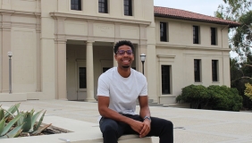 Micah Wilson '22 seated on bench outside of large academic building.