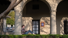 A student in Booth courtyard studying with their computer