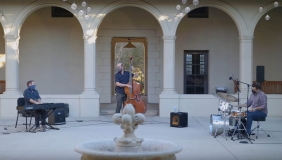 A jazz trio of piano, bass, and drums performing in the Booth Hall courtyard