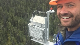 Troy Magney above trees with hard hat and equipment