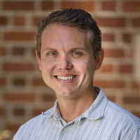 Dustin Madison headshot in front of brick wall