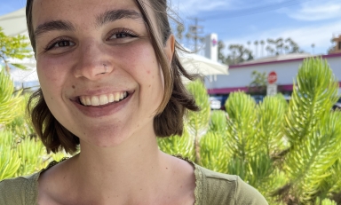 Image of Corinne Maiorano in green shirt, with green plants and blue sky in background