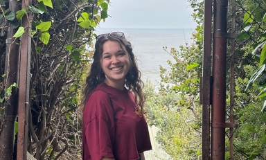 Image of Abby Smith in maroon shirt, with green trees in background