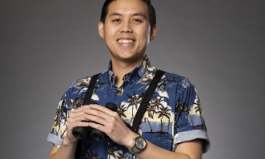 Man with binoculars in front of gray background