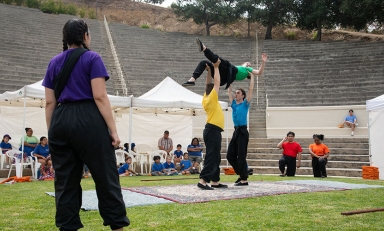 Members of Occidental Children's Theater perform on the grass in brightly colored tshirts