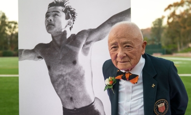 Sammy Lee Occidental College Olympian standing in front of a photo of him as a young man diving