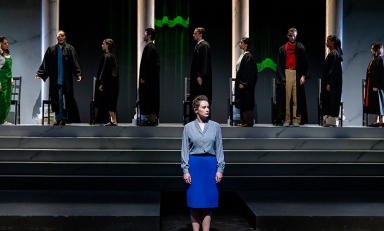 woman standing on stage with a simulated court of supreme court judges behind her
