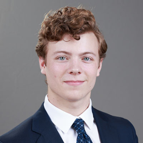 Tommy Quick headshot in business suit, red hair