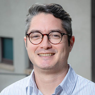 Joel Walsh headshot with collared shirt and glasses