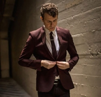 Composer Matt Ray buttoning up a maroon suit jacket