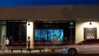 People stand in front of the Oxy Arts building at night, wit