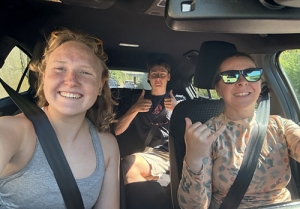 Two Occidental students and their professor pictured together in a car.