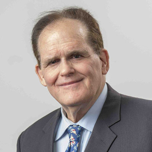 Stephen Fluharty headshot in grey suit jacket and tie