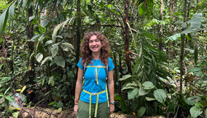 a young woman stands smiling in the jungle