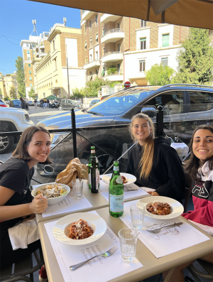 Three young women at a restaurant table in the afternoon on the streets of Rome