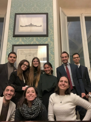 A group of colleagues posing together in a tall-ceilinged Italian conference room